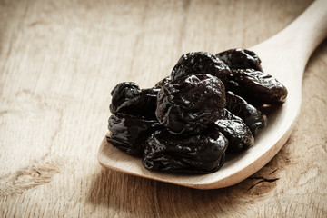 dried plums prunes on wooden spoon