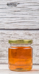 Honey in a mason jar over rustic weathered wooden background