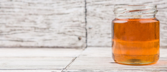 Honey in a mason jar over rustic weathered wooden background