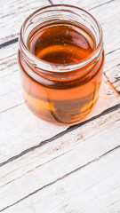Honey in a mason jar over rustic weathered wooden background
