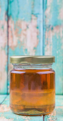 Honey in a mason jar over rustic weathered wooden background