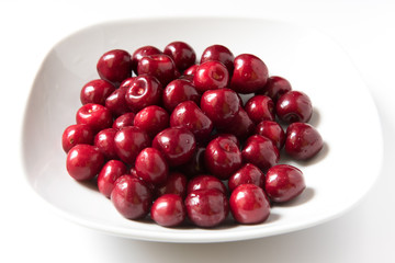Bowl of red fresh cerries on a white background
