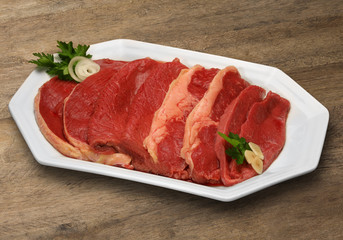 Raw meat selection on wooden cutting board with knife