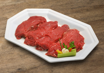 Raw meat selection on wooden cutting board with knife
