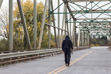 horizontal image of a very troubled man walking in the middle of the road over a steel bridge...