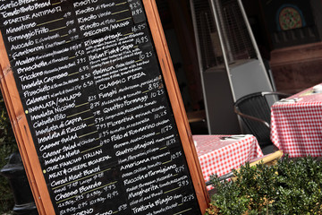Italian restaurant with menu chalk board and customer seating tables in the background photo