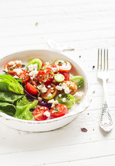salad with cherry tomatoes and soft cheese on a vintage plate on a light background