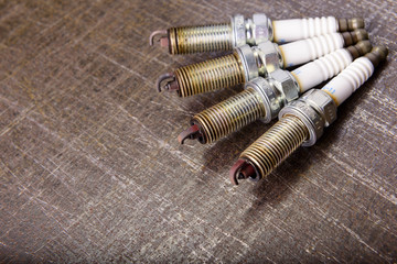 Four spark plugs on a metal background.