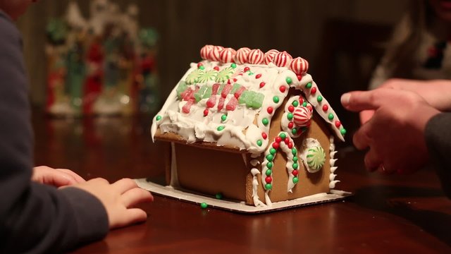 Happy family making gingerbread house together at home before Christmas. 