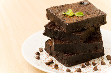 Stack of homemade brownie with chocolate chip on white plate