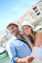 Fototapeta na wymiar Couple of tourists at seaside resort looking at city map