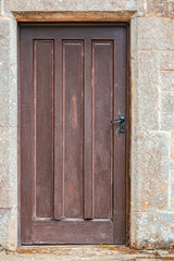 Old wooden door set in a rectangular frame in a stone wall