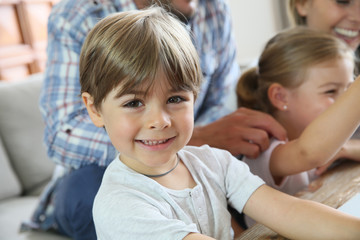 Portrait of smiling 4-year-old boy, family in background