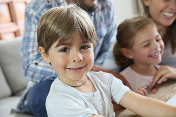 Fototapeta premium Portrait of smiling 4-year-old boy, family in background