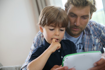 Daddy with kid playing with video game player © goodluz