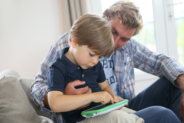 Daddy with kid playing with video game player © goodluz