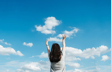 A young woman stretches her hand towards the sky