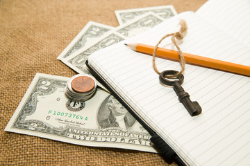 Opened notebook, pencil, key and money on the old tissue