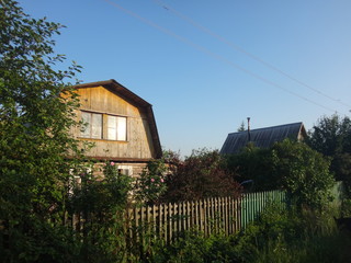 Дом в деревне, окружённый зеленью в летний солнечный день