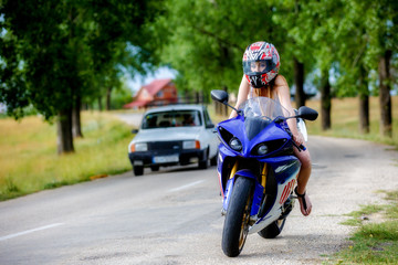 beautiful young woman with a motorcycle speed in nature