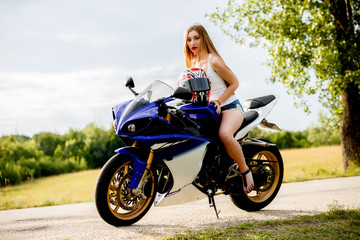 Obraz na płótnie Canvas beautiful young woman with a motorcycle speed in nature