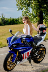 Obraz na płótnie Canvas beautiful young woman with a motorcycle speed in nature