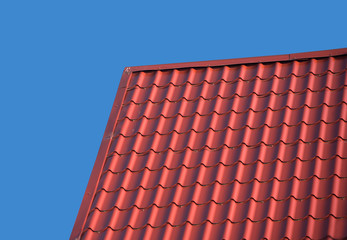 Top of country house roof covered with metal tile isolated on blue closeup