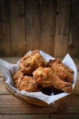 Fried Chicken in a basket on a wooden floor.