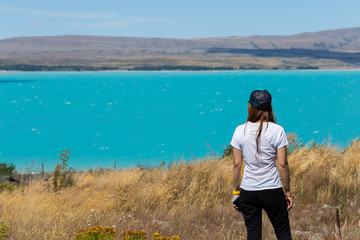 back view of woman standing and looking out towards turquoise la