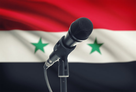 Microphone on stand with national flag on background - Syria