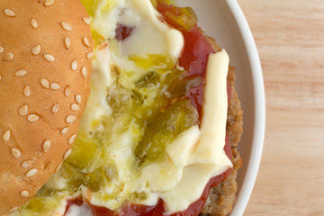 Cheeseburger covered with condiments on a small plate