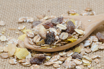 Oat flakes in wooden spoon on sackcloth background