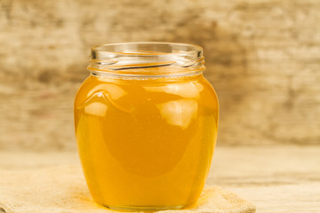 glass jar of fresh honey on wooden background