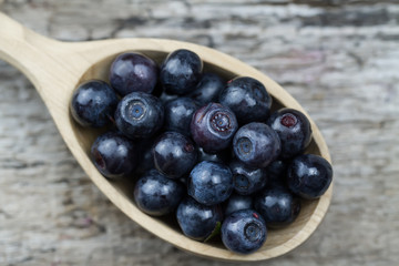 fresh blueberries in spoon on wooden background, close-up