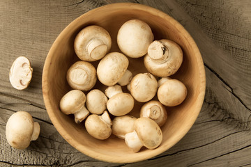fresh mushrooms on a plate on wooden background, top view