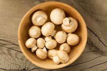 fresh mushrooms on a plate on wooden background, top view