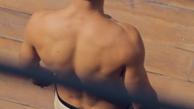 Muscular guy in swimming trunks goes on the wooden pier outdoors