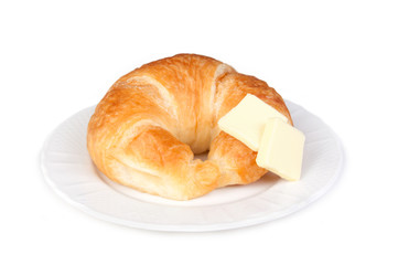 Croissant with Butter Pats – A single croissant, with two butter pats. On a white plate. Isolated...