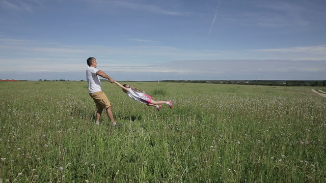 father playing with his daughter in field 