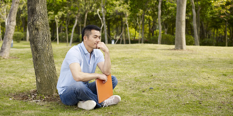 asian man thinking outdoors