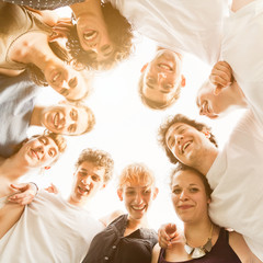 Group of ten young teenagers friends gathered to form a circle in the park, embraced each other....