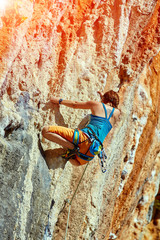 Fototapeta premium Rock climber climbing up a cliff