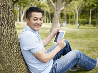 asian man using tablet outdoors