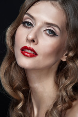 Fototapeta premium Portrait of beautiful young women with red lips, wavy hair, black eyeliner. Beauty. Studio shot. Black background.