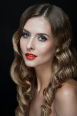 Fototapeta premium Portrait of beautiful young women with red lips, wavy hair, black eyeliner. Beauty. Studio shot. Black background.