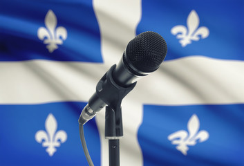 Microphone on stand with Canadian province flag on background - Quebec