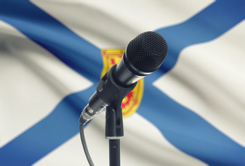 Microphone on stand with Canadian province flag on background - Nova Scotia