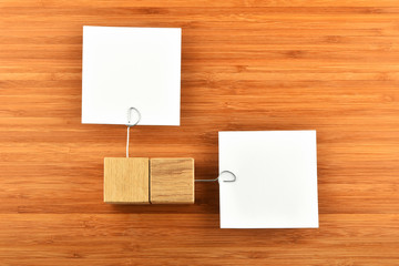 Two paper notes with wooden holders different directions on wood