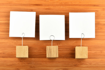 Three paper notes with holders on wooden background