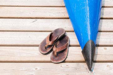 well worn sandals on a dock with a kayak